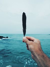 Close-up of hand holding sea against sky