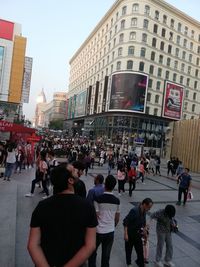 People walking on road against buildings in city