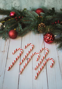 Candy canes on white wood backdrop with christmas decorations.