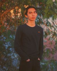 Portrait of young man standing against trees