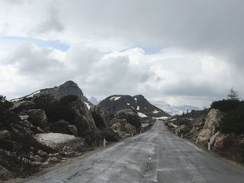 Road leading towards mountain against sky