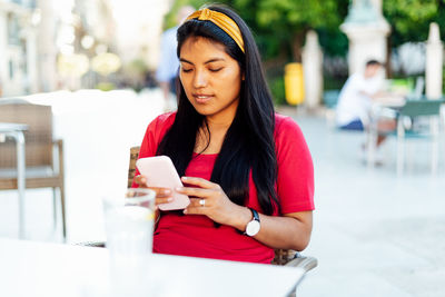 Young woman using mobile phone while sitting outdoors