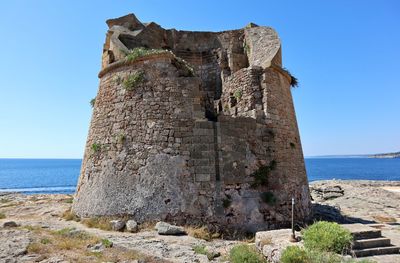 View of rock formation by sea against clear sky