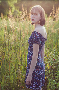 Portrait of young woman standing at field