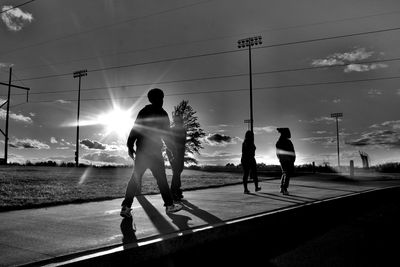 Silhouette people against sky in city during sunset