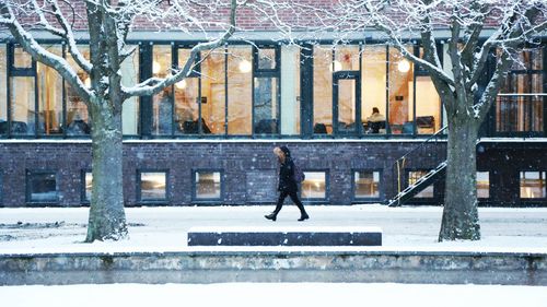 Side view of man walking on snow covered city