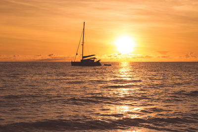 Silhouette boat in sea against sky during sunset