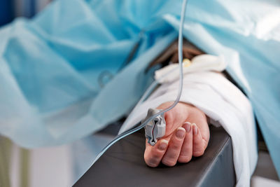 Close-up of human hand on bed
