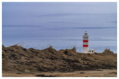 Lighthouse by sea against sky