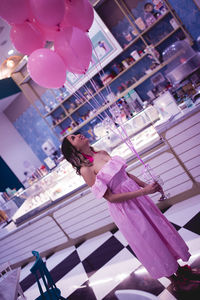 Woman with pink balloons standing in restaurant