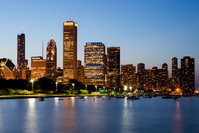 Illuminated buildings in city against clear sky