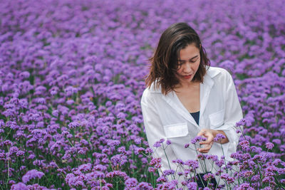 Young woman with purple flowers on field