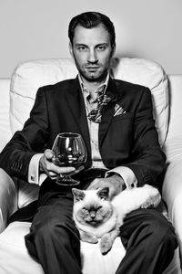 Portrait of man with cat sitting on armchair