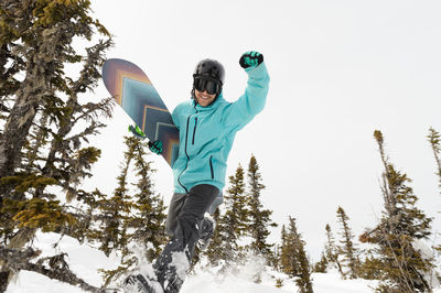Portrait of man with snowboard against clear sky