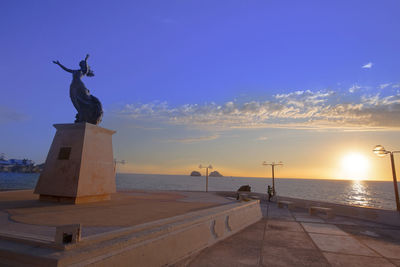 Statue by sea against sky during sunset