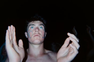 Close-up of shirtless man against black background