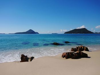 Scenic view of beach against clear blue sky