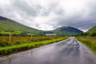 Country road amidst landscape against sky