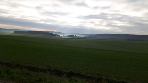 Scenic view of grassy field against cloudy sky