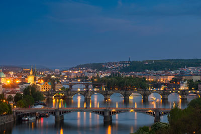 Illuminated bridge over river against sky at night