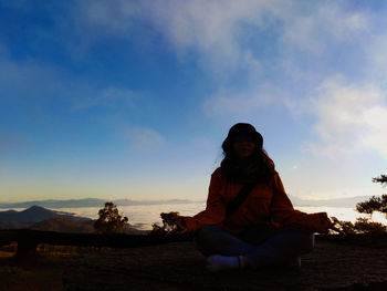 Full length of woman meditating against sky during sunset