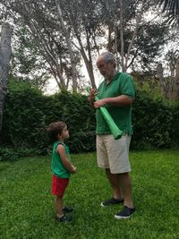 Full length of boys standing on grass against trees