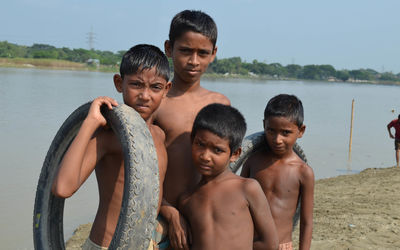 Portrait of boys holding tires while standing outdoors