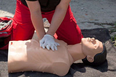 Midsection of lifeguard performing cpr on mannequin