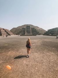 Rear view of woman standing on land against clear sky