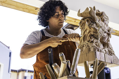 Sculptress carving wooden figure in the job