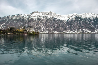 Scenic view of lake by snowcapped mountains against sky