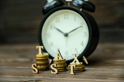 Close-up of coins with tax text and alarm clock on table