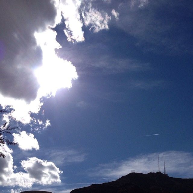 sky, low angle view, cloud - sky, sun, tranquility, sunbeam, beauty in nature, tranquil scene, scenics, sunlight, cloud, nature, cloudy, mountain, blue, lens flare, idyllic, cloudscape, outdoors, silhouette