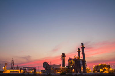 Illuminated factory against sky during sunset