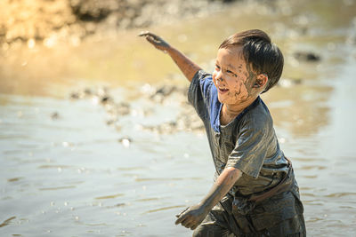 Smiling boy playing on mud outdoors