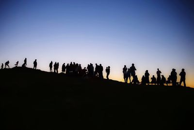 Silhouette people against clear sky during sunset