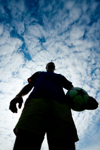 Low angle view of man standing against cloudy sky