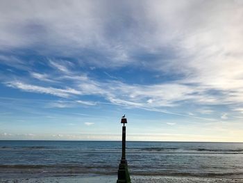 Lighthouse by sea against blue sky