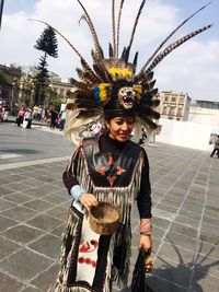 Woman in traditional clothing standing on street against sky