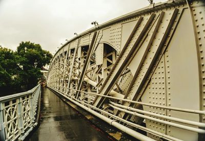 Footpath by bridge against sky