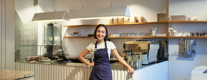 Portrait of young woman standing in kitchen