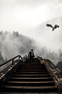 Low angle view of man walking down stairs against sky