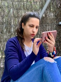 Teenage girl looking away while sitting on mobile phone