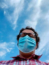 Low angle portrait of woman against blue sky