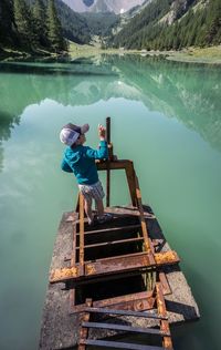 Rear vie of boy standing on built structure in lake