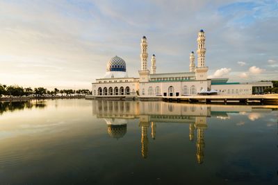 Reflection of temple in lake against cloudy sky