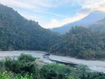 Scenic view of river by mountains against sky