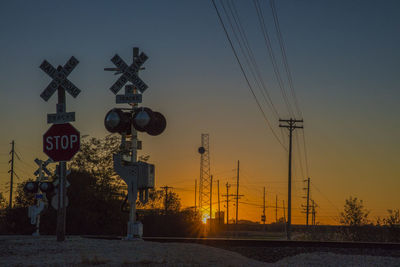 Power lines against sky at sunset