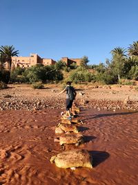 Rear view of man crossing a river