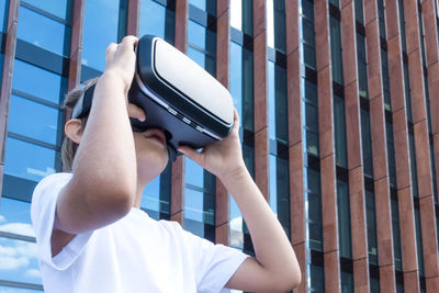 Girl wearing virtual reality simulator against building